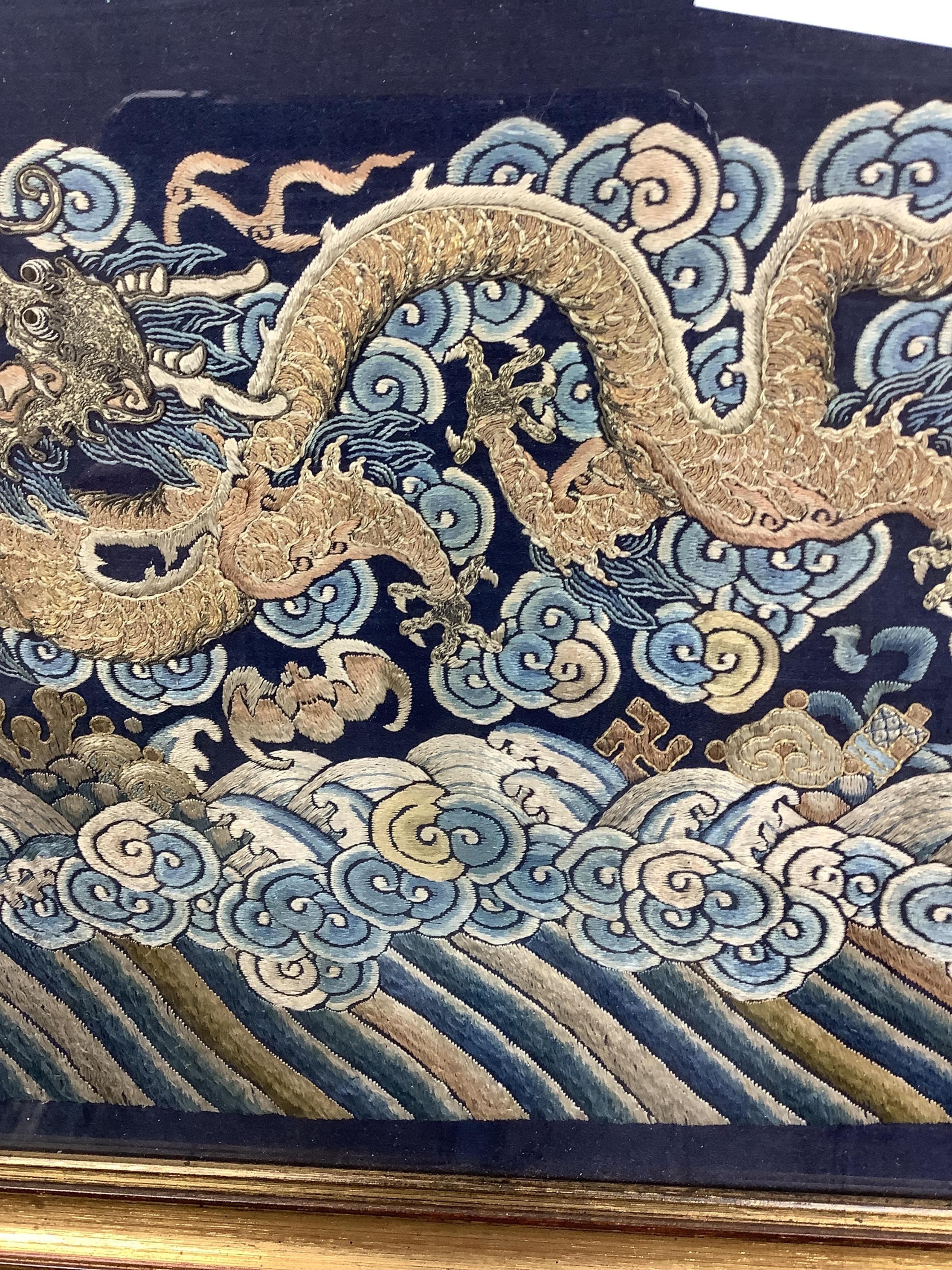 A framed late 19th / early 20th century Chinese silk embroidered five claw dragon panel from the base of a robe, 59cm wide x 23cm high. Condition - good, colours and embroidery strong